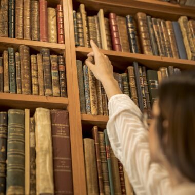 estudiante-elegante-que-busca-libro-biblioteca